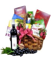 Red wine with assorted chocolates, cookies and snacks in a basket
